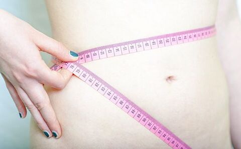 Ein Mädchen misst ihre Taille, um die Ergebnisse der Dukan-Diät aufzuzeichnen